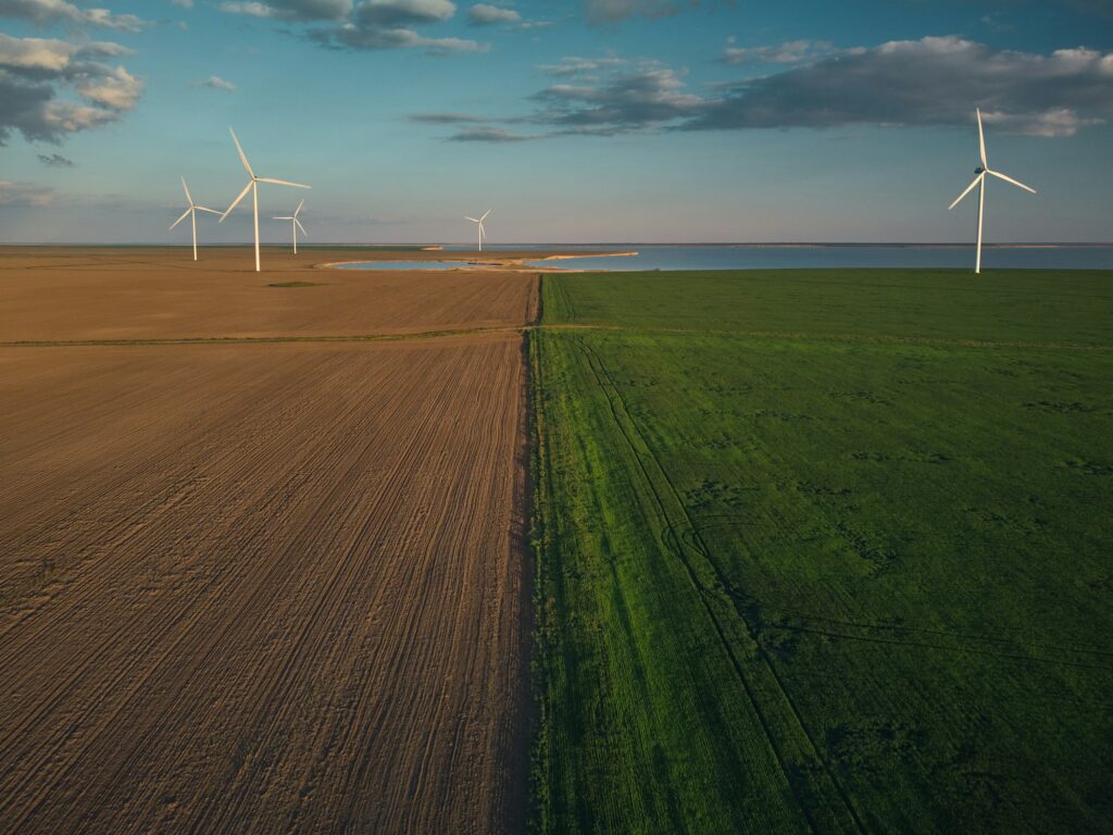 Aerial view of wind turbines and agriculture field near the sea at sunset