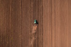 Agricultural tractor vehicle with tiller attached performing field tillage before the sowing season